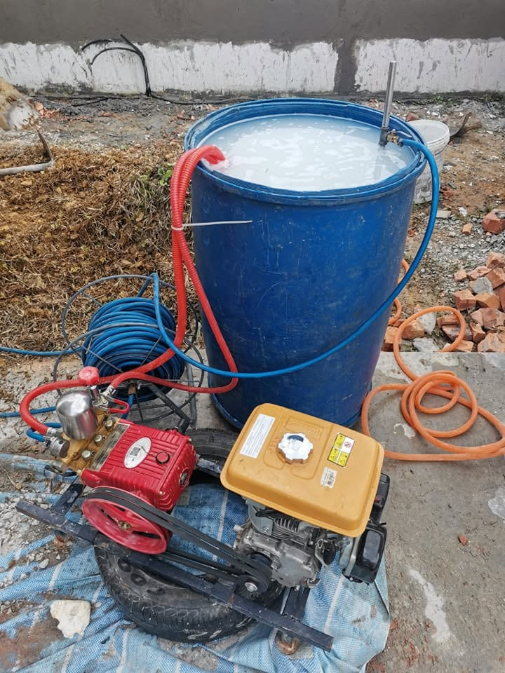 建筑工地上的汽油抽水泵和一个装着白色药液的 200 公升药桶。